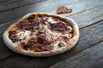 Variations on a heart shaped dried chilli and a pizza is laying on the nice old wooden table