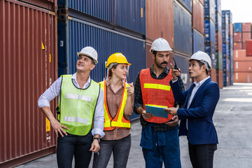 Group of staff worker standing and checking the containers box from cargo ship for export and import
