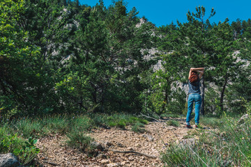 A full body shot of an unrecognizable young Caucasian female hiker standing with arms up on a path in the French Alps mountains on a sunny summer day