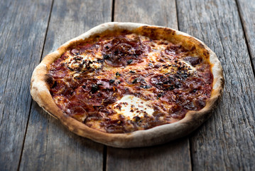 Isolated napolian styled pizza is laying down on a nice old wooden table, ideal for placing text next to the pizza.
