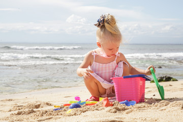 Summer vacation. Adorable toddler girl playing with beach toys on the sandy beach.
