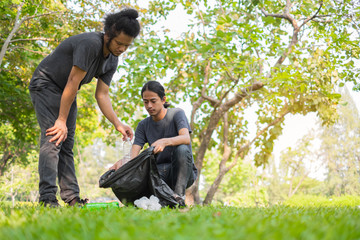 Group of Asian young volunteers picking up trash in park. Concept of environmental protection