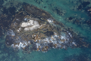 Sea water runs a wave on coastal stones and breaks against them.