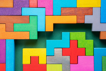 Colorful maze on green background. Labyrinth of colorful wooden blocks, top view, flat lay.