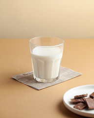  Glass of milk, chocolate on a white plate. The concept of farm dairy products, the use of milk. Copy space.