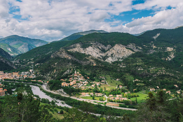 Naklejka na ściany i meble A picturesque wide panoramic view of a French village in the valley of Var in the Alps mountains (Puget-Theniers, Alpes-Maritimes, France)