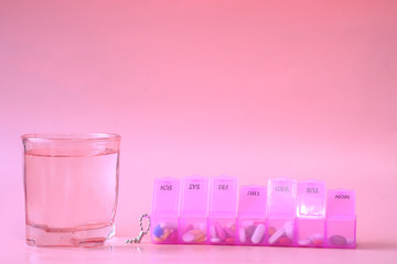  pill box and water glass on pink 