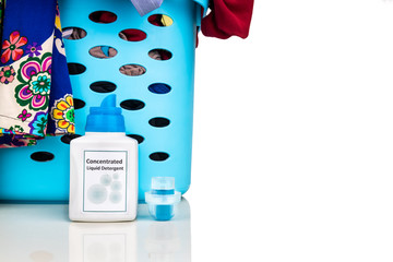 Tecnologically innovative compact concentrated laundry liquid detergent next to basket of clothes