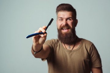 Bearded man with stylish hairdo. Barbershop advertising. Barber man holds straight razor.