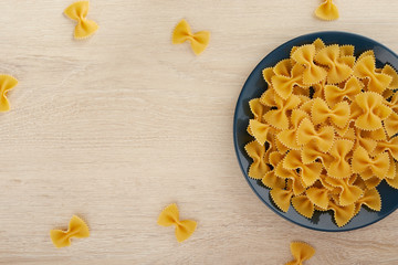 Raw pasta in the shape of a bow on a plate, top view, copy space