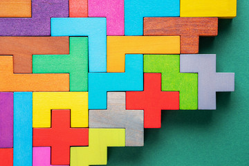 Different colorful shapes wooden blocks on green background, flat lay.