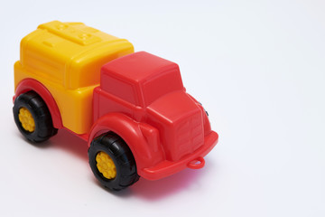 Fototapeta premium Colorful Children's toy car truck with a red cab and a yellow plastic body on a white background. Flat lay. Copy space.
