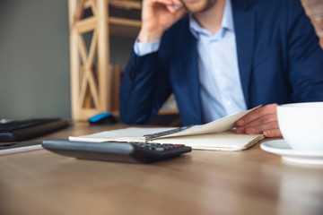 Close up of young man, manager return to work in his office after quarantine, feels happy and inspired. Writing, counting, analyzing. Coming back to normal life. Business, finance, emotions concept.