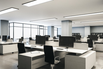 Modern office with computers on desk and city view.