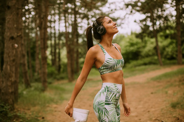 Young woman stretching and breathing fresh air in middle of forest while exercising