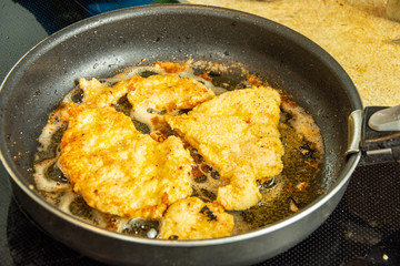 Chicken breast in batter and breading in a pan. Fresh fried meat. Chop cooked with pepper and Italian spices