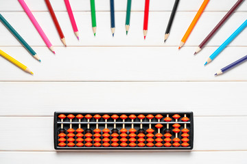 Abacus and colorful pencils on white wooden desk. Copy space. Education school of mental math,...