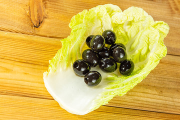 Olives on lettuce on a wooden background. Vegan healthy food.