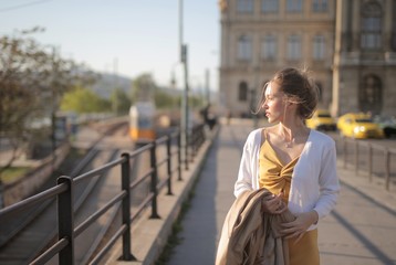 Attractive young woman in a yellow dress walking through the streets under the sunlight in Hungary
