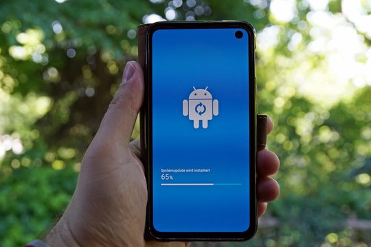 Eine Person h&auml;lt ein Smartphone in der Hand auf dem ein Android Softwareupdate l&auml;uft