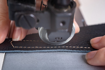girl sews on a sewing machine scribbles fabric and leather making a product