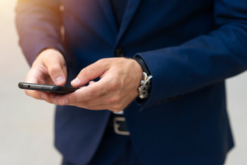 Man in suit holding phone and sending text closeup