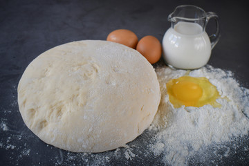 A set for baking bread with green ears of wheat and eggs on a dark countertop