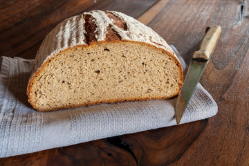 Close up of a delicious, crusty sliced bread on wood old table with knife