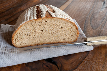 Fresh crisp bread with caraway on wooden table and knife
