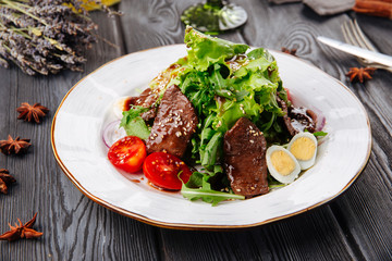 Gourmet beef and arugula salad on the wooden table