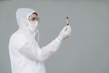 Corona virus theme. Man in a protective suit. Doctor looks at the blood tube.