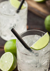 Gimlet Kamikaze cocktail in crystal glasses with lime slice and ice on wooden board.