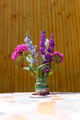 lilac flowers in a glass vase on the table in front of a rustic fence