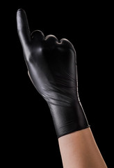 Hand in black gloves with the index finger pointing up on black