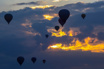 Many passenger balloons fly against the background of dawn in the clouds