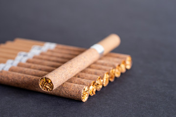 brown cigarettes with a filter on a background of black textured paper