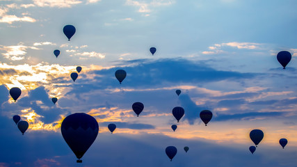 Many passenger balloons fly against the background of dawn in the clouds