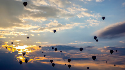 Many passenger balloons fly against the background of dawn in the clouds