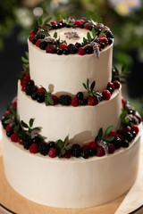 Beautiful three-tiered wedding cake decorated with natural berries: raspberries, blueberries, strawberries.