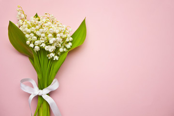 Lily of the valley flowers. Bouquet of Lily of the valley flowers on pink background. Flat lay, top view, copy space.