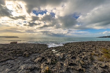 Fototapeta na wymiar Sunset over the sea with rocks and cloudy sky