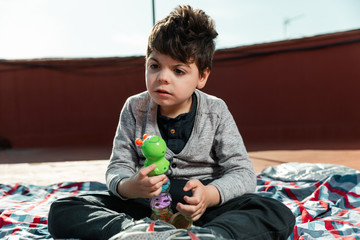 hay un niño de 5 años jugando en la terraza de una casa con un juguete de plástico, tipo...