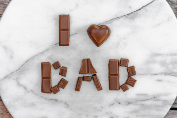 Celebrating Father's Day or birthday. Phrase I love dad laid out in chocolate letters on a marble...