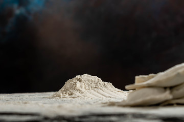 montaña de harina con ravioles desenfocados con fondo oscuro