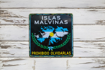 Sign plate with 'Islas Malvinas - forbidden to forget' words on old white wooden wall in Ushuaia...