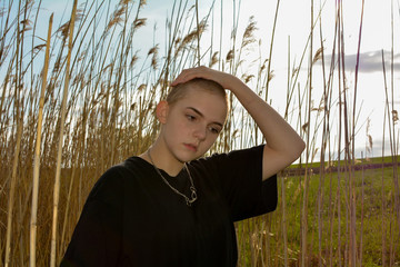 Girl  with very short hair  in nature, hand on the top of the head