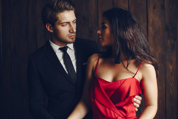 Elegant man in a black suit. Couple at home. Hot woman in a red dress