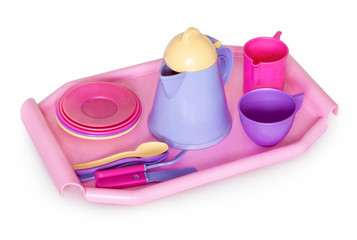 Childish kitchenware. Children's kitchen utensils on a tray, a toy. Plates spoon, knife, fork, tea cups, teapot. Isolated on white background with natural shadow.