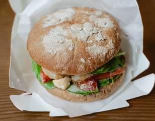 hamburger with dark flour with vegetables and shrimp on a wooden background