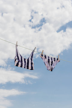 Two pieces swimsuit hanging in a clothes line against blue sky. Summer concept.